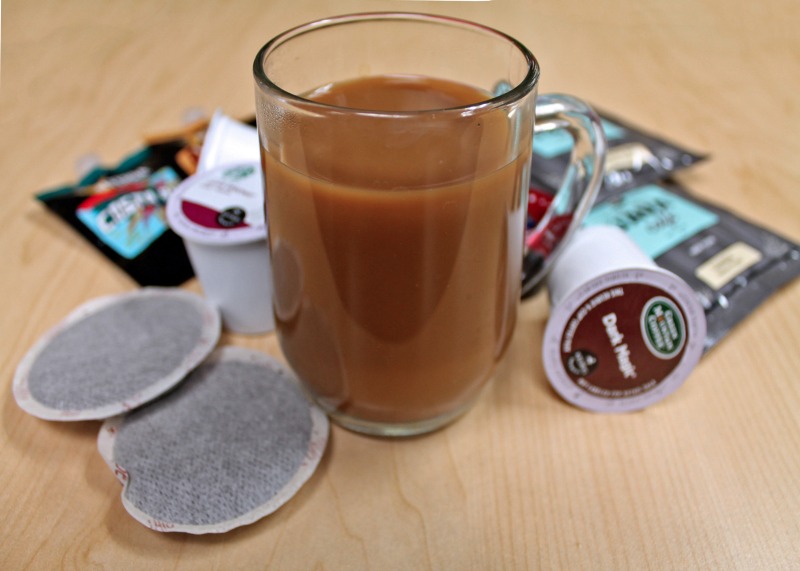 a cup of coffee on a table with coffee bags